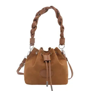 Sac seau en daim marron avec poignée tressée et bandoulière réglable sur fond blanc