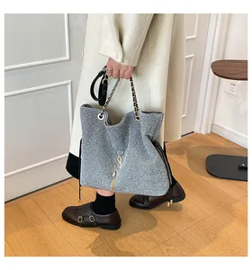 Detail der glitzernden silbernen Tweed-Tasche mit Goldkette und S-Logo-Anhänger