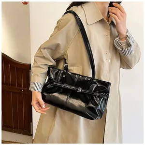 Détail du sac porté épaule noir brillant avec boucle de ceinture et œillets métalliques