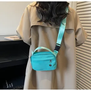 Détail du sac bandoulière en nylon turquoise avec logo en métal et bandoulière tissée