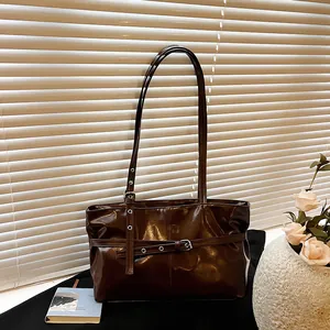Sac sous le bras marron foncé brillant avec de longues bretelles et des œillets en métal