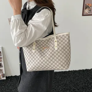 Minimalist beige tote bag with M letter pattern and golden bow buckle on shoulder strap