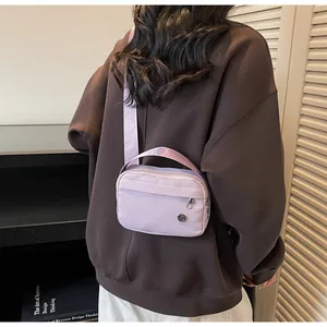 Vue arrière d'une personne portant un sac bandoulière en nylon violet clair en intérieur