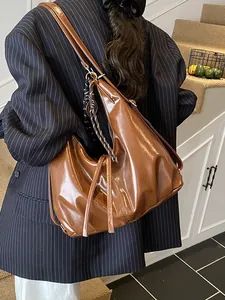 Braune Shopper-Tasche aus Ölwachs-Leder mit dekorativem Seidentuch an der Seite getragen