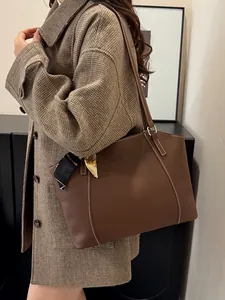 Brown leather tote bag with white contrast stitching and decorative silk scarf detail
