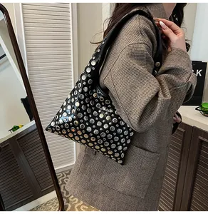 Detail of black leather underarm bag with silver rivets worn by a model