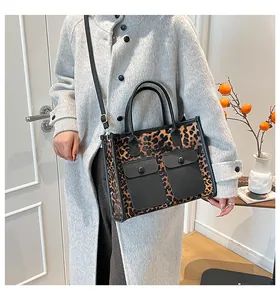 Détail d'un sac cabas léopard avec poches en cuir noir et bandoulière réglable