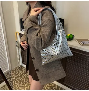 Close-up of metallic silver shoulder bag with round rivets on model in casual suit