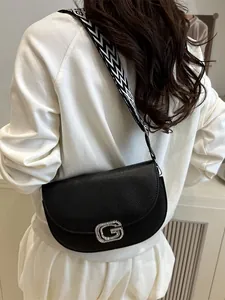 Women's black textured leather crossbody saddle bag with geometric woven strap and silver G buckle