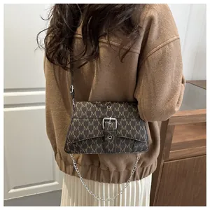 Tragebeispiel der braunen Umhängetasche mit M-Muster und modischer Metallkette