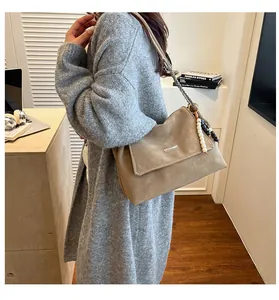Détail du sac hobo latte avec chaîne argentée et breloques perlées dans un décor douillet