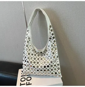 Detailed view of white hobo bag with silver round rivets on glossy leather surface