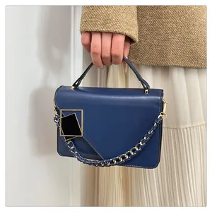 Gros plan du sac bandoulière bleu marine avec boucle dorée et bandoulière en chaîne