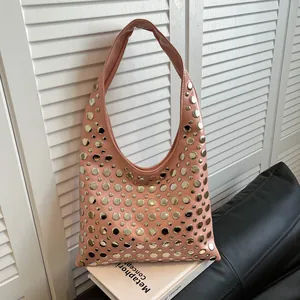 Pink leather hobo bag with metallic silver studs and rivets in a modern urban setting