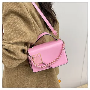 Détail du sac à main rose avec boucle dorée porté sur un manteau en tweed marron