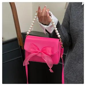 Détail du sac à main rose avec grand nœud en organza et chaîne de poignée en perles