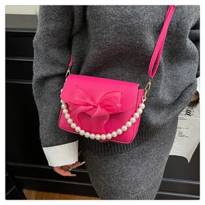 Détail du sac bandoulière rose fuchsia avec nœud en organza et poignée de perles