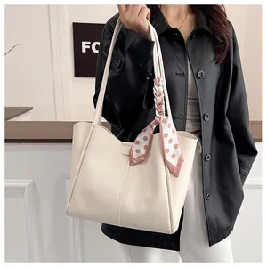 Detail of a beige PU leather tote bag with a pink polka dot scarf on the handle