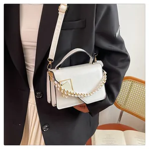 Détail du sac à bandoulière en cuir blanc avec boucle dorée et bandoulière chaîne