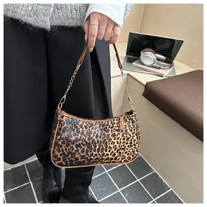 Detail of leopard print crescent bag with leather piping and gold metal chain strap