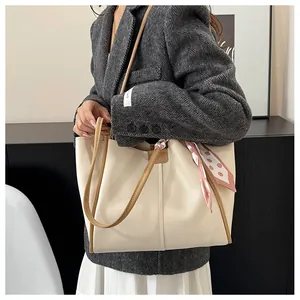 Detail of cream tote bag with brown trim and pink polka dot scarf on a suit model