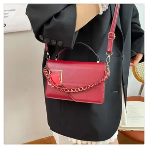 Détails du sac à bandoulière rouge avec boucle métallique et chaîne porté par un mannequin