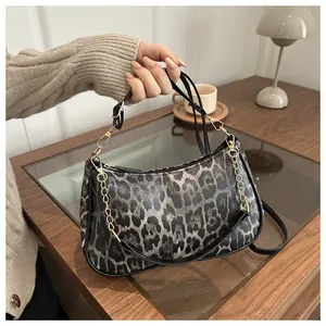 Close-up of leopard print crescent bag with gold chain strap in a cozy interior setting