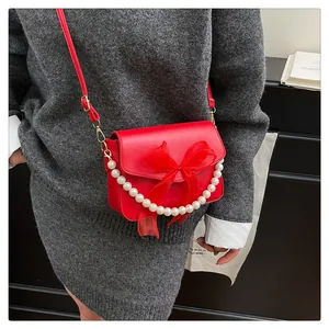 Détail du sac rouge en cuir avec noeud en tulle, chaîne perlée et dorures