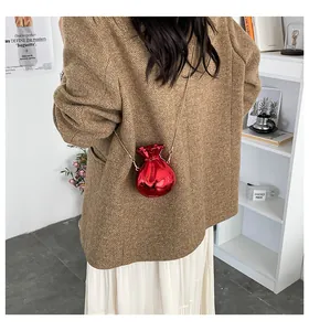Dettaglio della mini borsa rossa a forma di caramella con catena d'oro sul modello