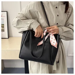 Detail view of black PU leather tote bag with decorative dotted silk scarf on handle