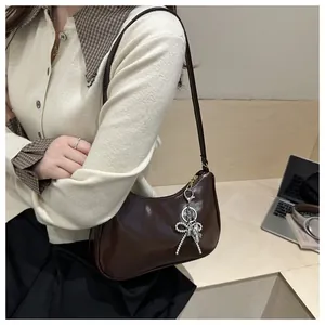 Λεπτομερής λήψη της σκούρας καφέ γυαλιστερής hobo τσάντας με ασημένιο φιόγκο