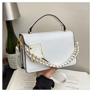 Détail d'un sac à main blanc carré avec fermoir doré et grosse chaîne tressée