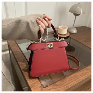Detailaufnahme einer roten Trapez-Handtasche mit goldener Schnalle auf einem Holzschreibtisch