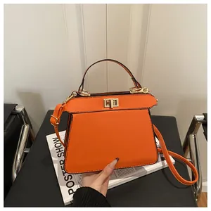 Detailansicht einer orangen Ledertasche mit Goldverschluss und Akkordeon-Seitenfalten