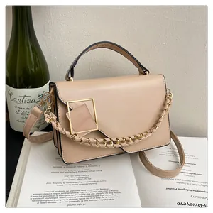Détail du sac à main kaki avec boucle dorée et poignée chaîne posé sur un livre