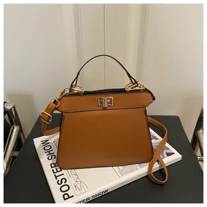 Details einer braunen Ledertasche mit goldenem Drehverschluss und verstellbarem Gurt