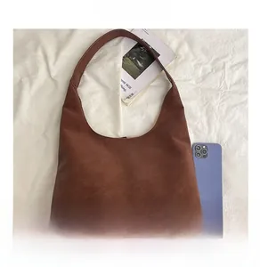 Macro detail of large brown leather tote bag with wide shoulder strap on white background