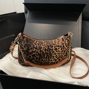 Retro leopard print crescent underarm bag with gold chain and leather strap on white fabric