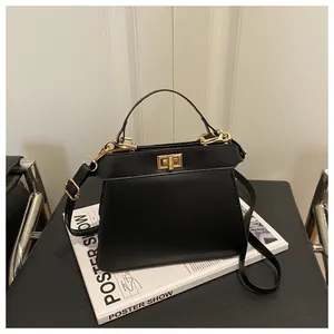 Detail einer schwarzen Trapez-Handtasche aus Leder mit goldenem Drehverschluss