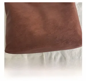 Detail shot of brown leather tote bag with vintage texture and stitched logo patch