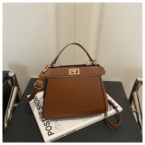 Detailansicht der braunen Leder-Trapeztasche mit goldenem Drehverschluss und Griff