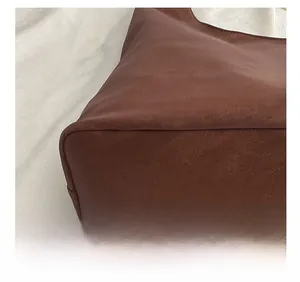 Close-up of precision stitching and leather texture on the bottom of a brown tote bag
