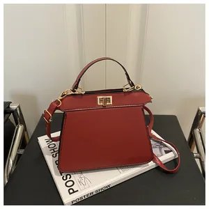Detailansicht der ziegelroten Leder-Trapeztasche mit goldenem Verschluss und Handgriff