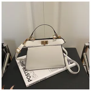 Detailansicht der weißen Trapezhandtasche mit goldenem Drehverschluss und Metallteilen