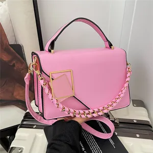 Sac à main rose en cuir PU avec boucle dorée et bandoulière sur valise blanche