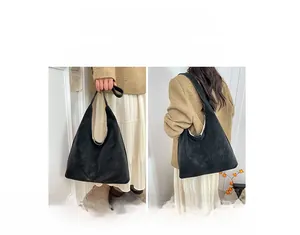 Detail view of black tote bag with wide strap showing single shoulder and handbag styles