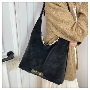 Close-up of black matte suede tote bag with yellow logo on a model in a stylish setting