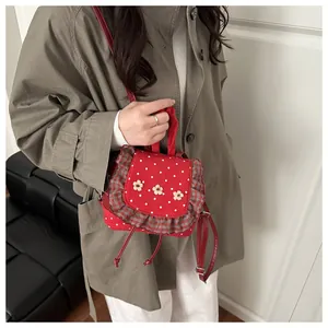 Détail du mini sac à dos rouge à pois avec broderie florale et bordure à carreaux