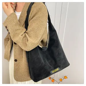 Close-up of black suede tote bag featuring yellow embossed logo and large capacity