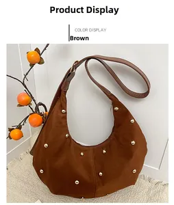 Detalle del bolso de media luna en ante marrón con tachuelas doradas y bandolera